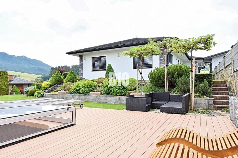 A family house in Súľov-Hradná with a terrace, swimming pool, and garden seating against the backdrop of mountains.