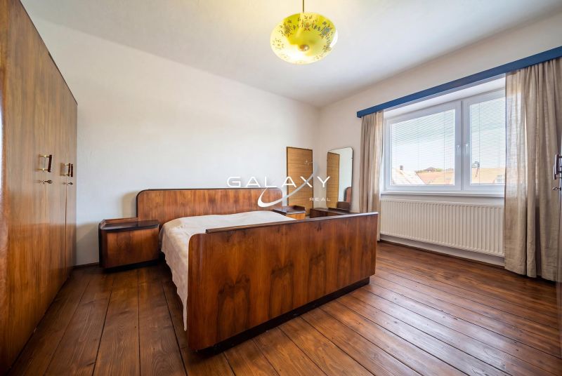 A bedroom in a family house with a wooden decor floor and retro furniture.