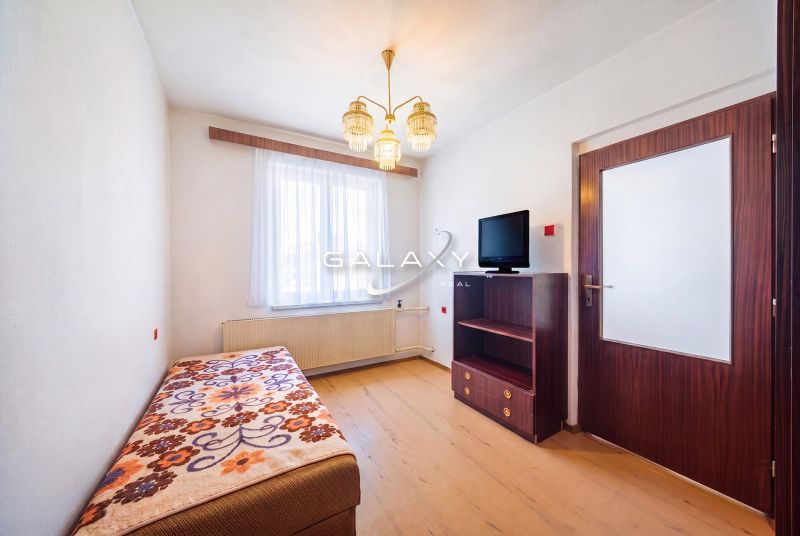 A room in a family house with a bed, a television, and a floor with a wooden decor.