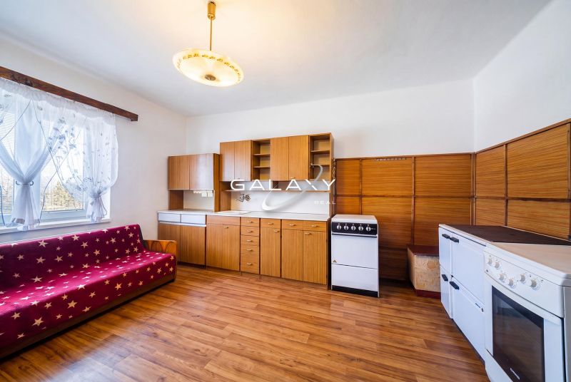 A kitchen in a family house with a kitchen unit, stove, and a floor with a wooden decor.