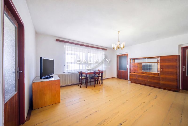 Living room in a family house with a wooden decor floor, furniture, and a television.