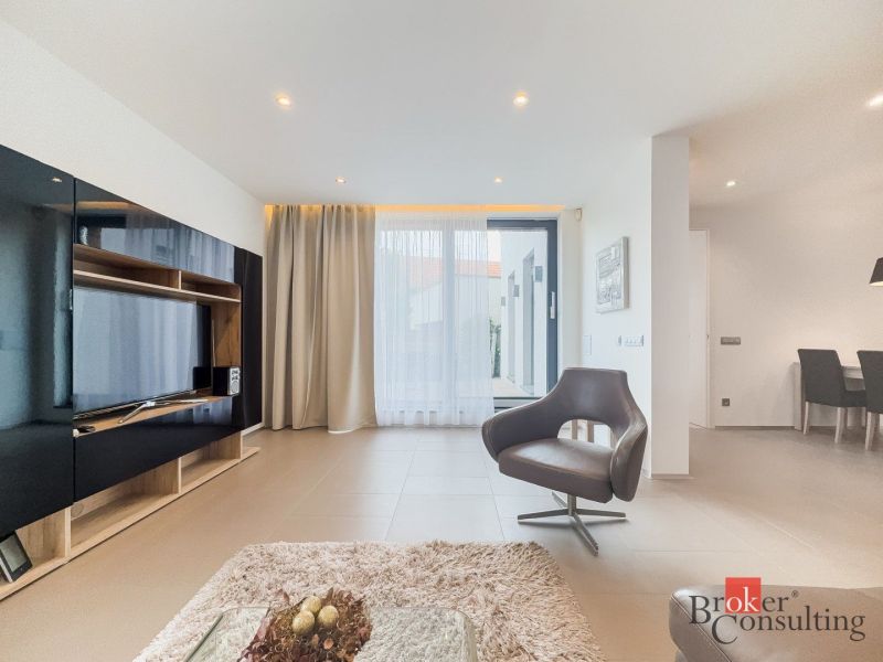 Living area in a 2-room apartment with a television and a comfortable armchair.