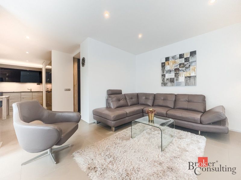 Living room in a 2-room apartment with a leather sofa and a glass table.