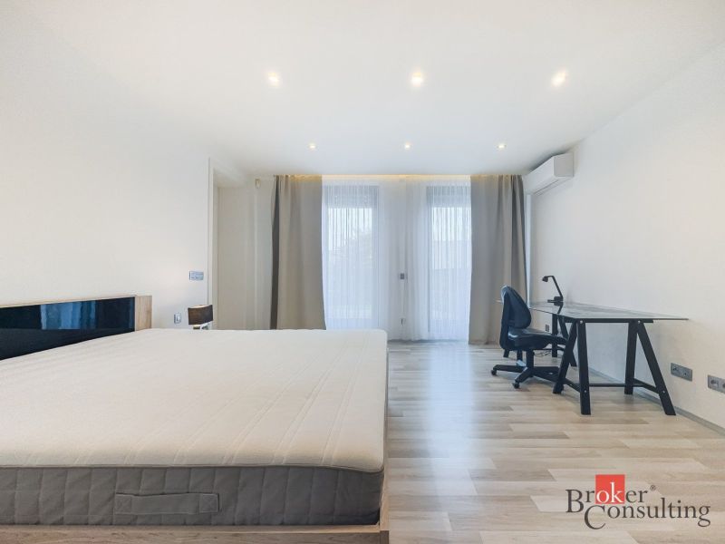 Bedroom in a two-room apartment with a wooden decor floor and a writing desk.