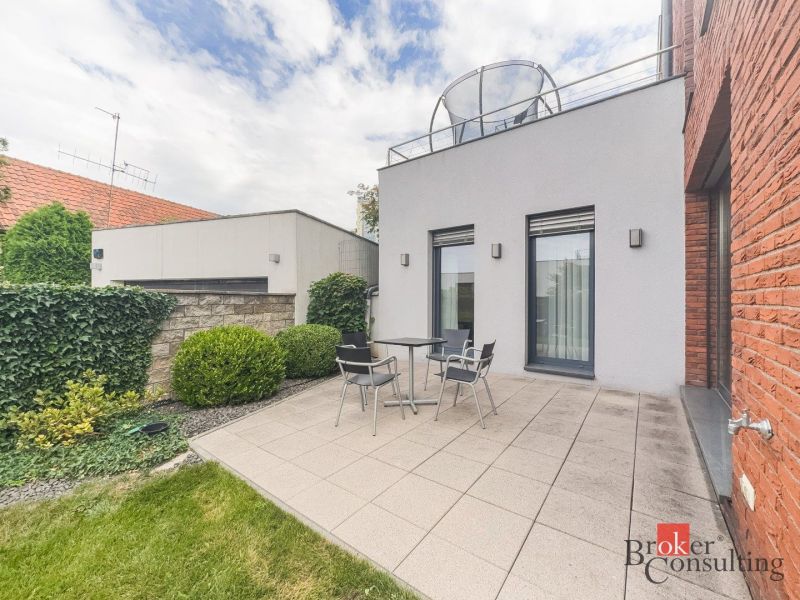 Terrace of a 2-room apartment with tiles, seating area surrounded by a green garden on Bárdošova Street.