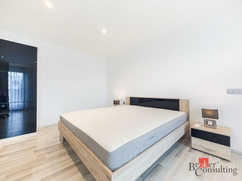 Bedroom in a 2-room apartment with wood-patterned flooring, a bed, and nightstands.