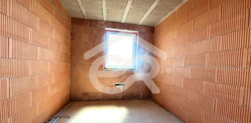 An unfinished room in a family house with construction bricks and a small window.