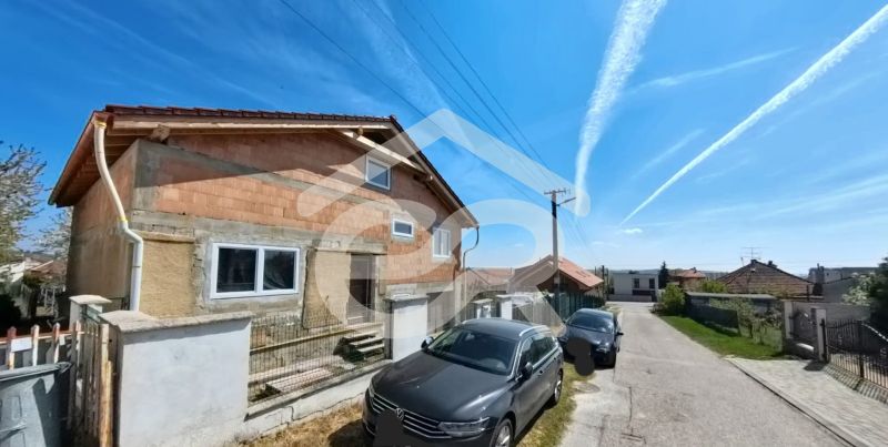A family house at Lehárova 2 in Nitrianske Hrnčiarovce with parked cars and a blue sky.