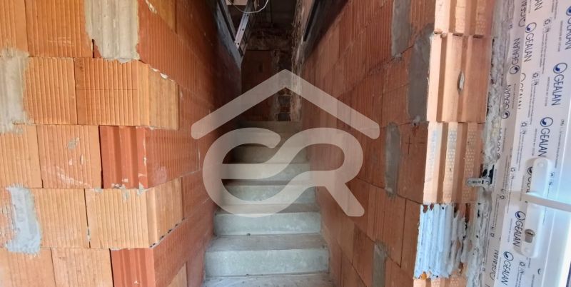 Unfinished staircase with raw brick walls in a family house.