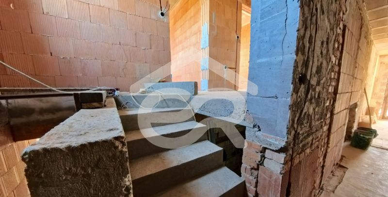 A staircase in an unfinished family house with brick walls and exposed wiring.