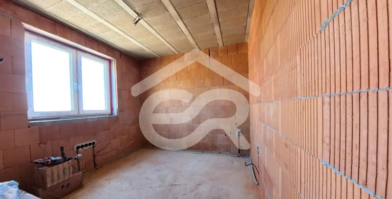 The interior of a family house with unfinished brick walls and a plastic window.