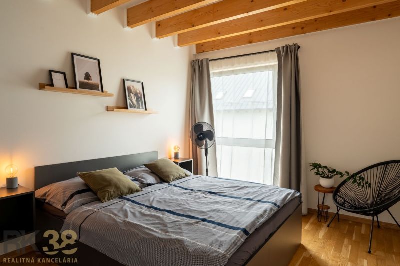 Bedroom with wood-patterned flooring, double bed, decorations, and an armchair in a 4-room apartment.