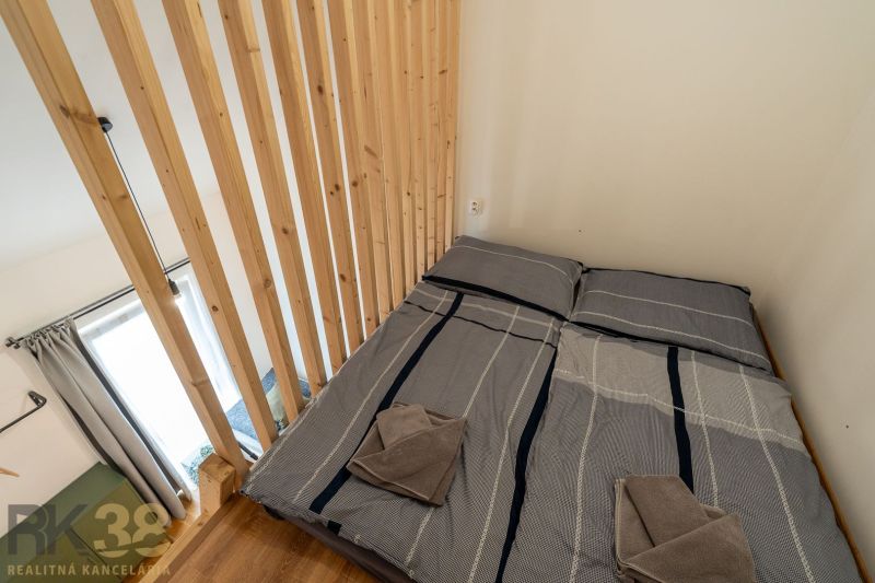 A bedroom in a 4-room apartment with a wooden structure and a bed with shirt-patterned bedding.