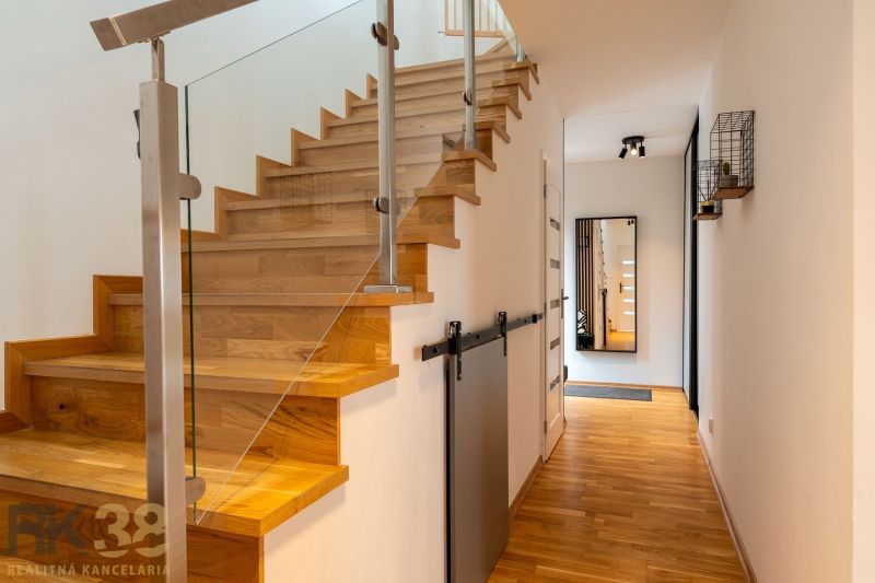 A hallway with stairs, a wooden decor floor, and a mirror in a 4-room apartment.