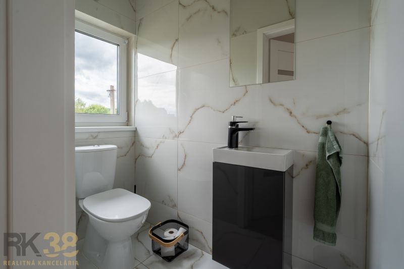 Bathroom with a mirror, sink, and toilet in a 4-room apartment, with marble design tiles.