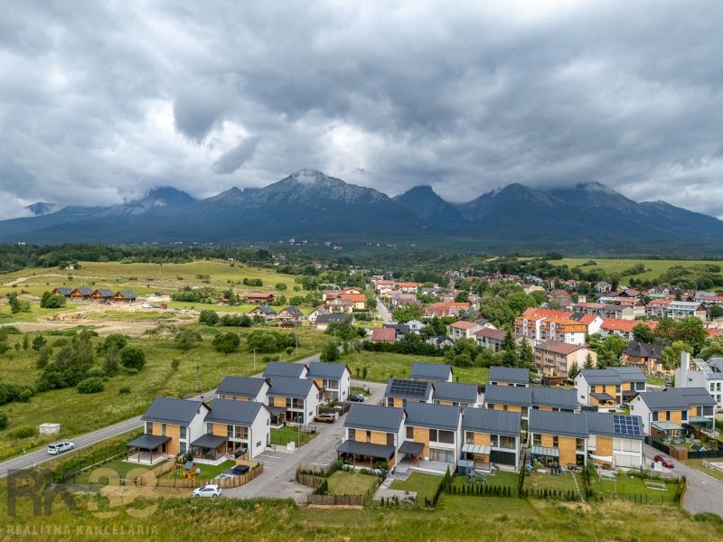 Nová Lesná, Vodárenská Street with a view of the mountains with new buildings and clouds.