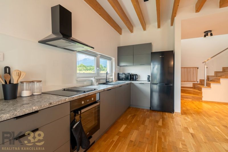 A kitchen in a 4-room apartment with a modern cooktop and flooring with a wood decor.