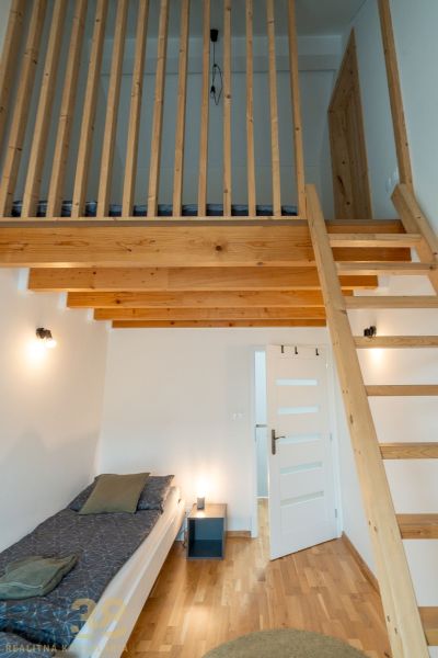 Loft bed with a wooden ladder and floor with a wooden decor in a 4-room apartment.