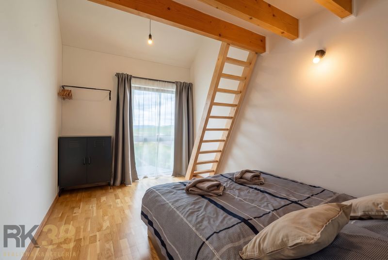 Bedroom in a 4-room apartment with a ladder, bed, and wooden decor flooring.