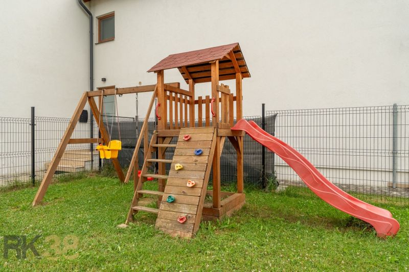 A children's climbing frame with a slide and a swing in the yard of a 4-room apartment on Vodárenská Street in Nová Lesná.