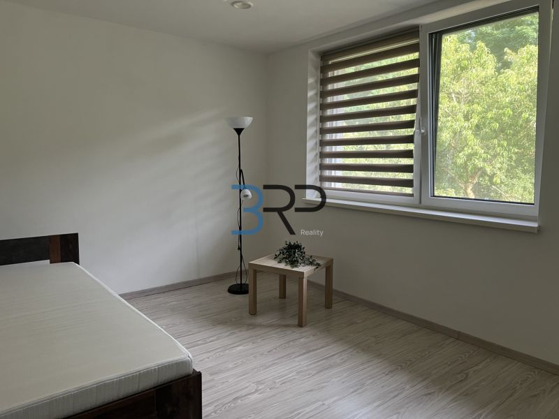 A minimalist room in a family house with a wood-patterned floor and a view of greenery.