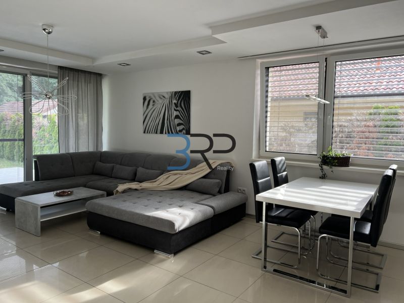 Living room of a family house with a corner sofa, a zebra poster, and a dining table.