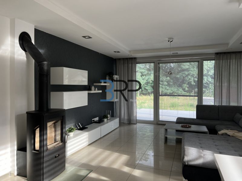 Living room in a family house with a fireplace, corner sofa, and large windows.