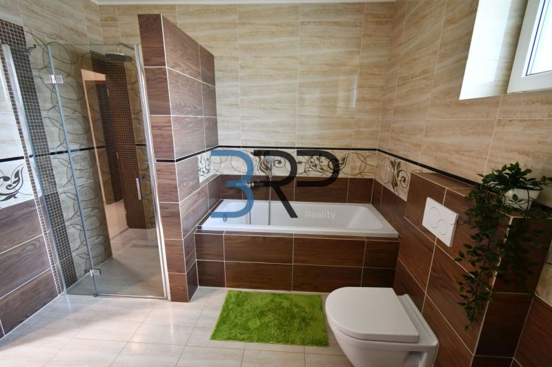 A bathroom in a family house with a bathtub tiled with wood-patterned tiles.