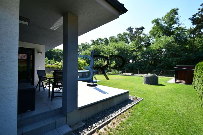 The garden of a family house in Šajdíkové Humence with a terrace and lawn surrounded by greenery.