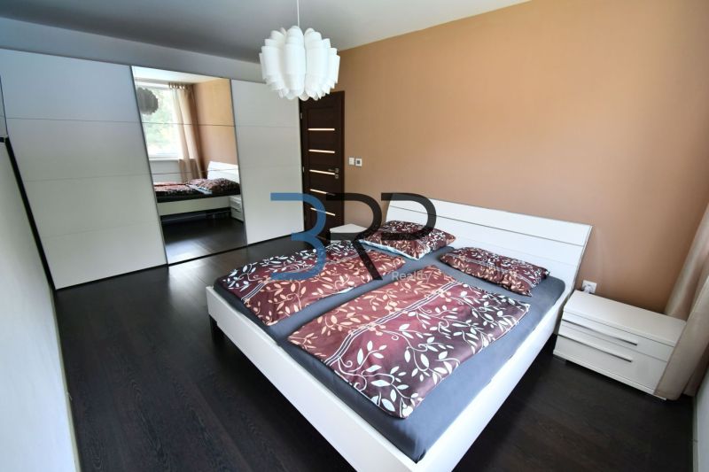 A bedroom in a family house with a dark floor, a large wardrobe, and a bed.