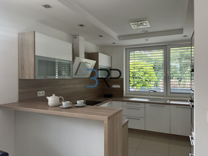 A kitchen in a family house with wooden decor, a large window, and appliances.