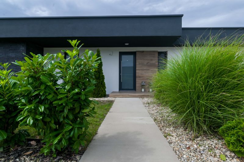 A family house in Košúty with a garden, a walkway, and modern shrubs in the front part.
