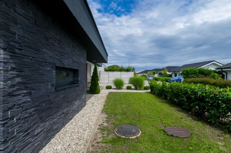 The exterior of a family house in Košúty with stone cladding and a garden.