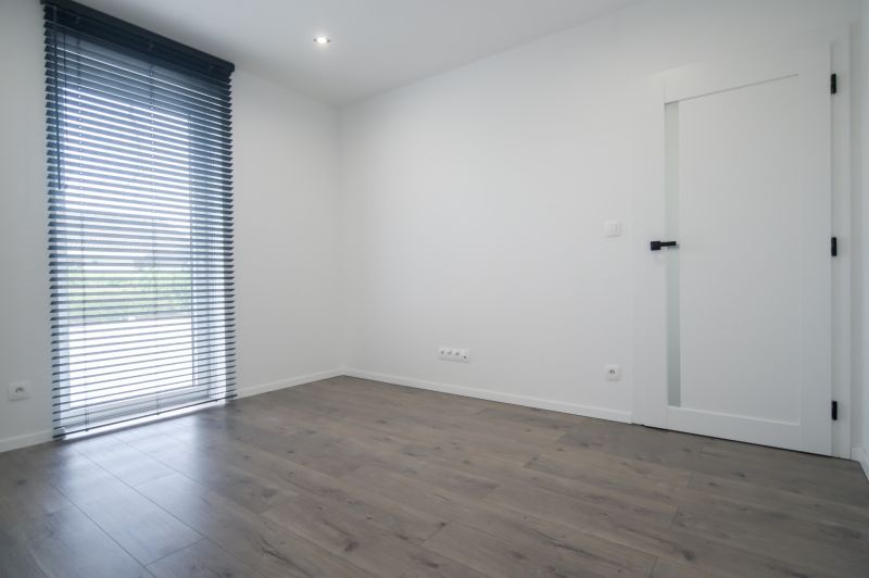 A room with a wooden decor floor, white walls, and vertical blinds in a family house.