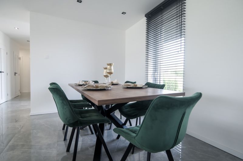 A dining room with a wooden table and green chairs in a family house.