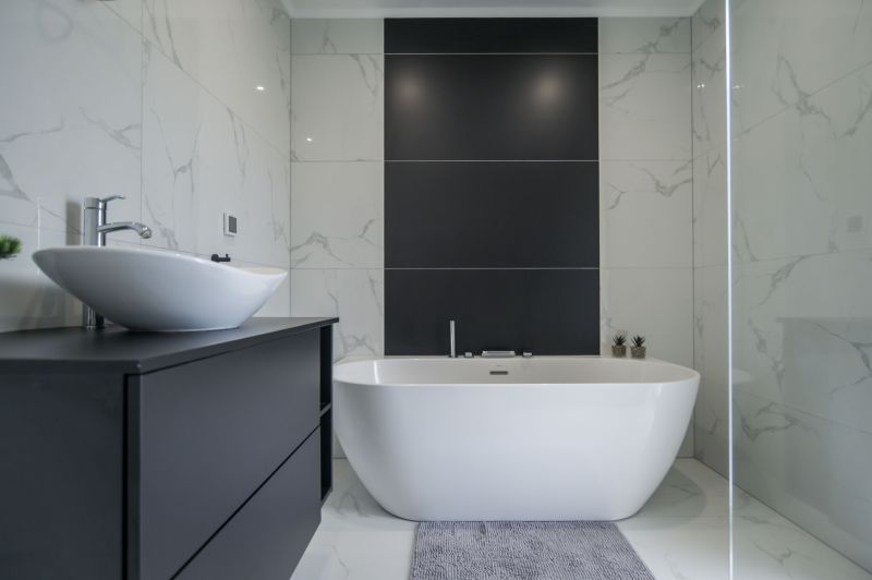 A bathroom in a family house with a bathtub, a sink, and tiles imitating marble.