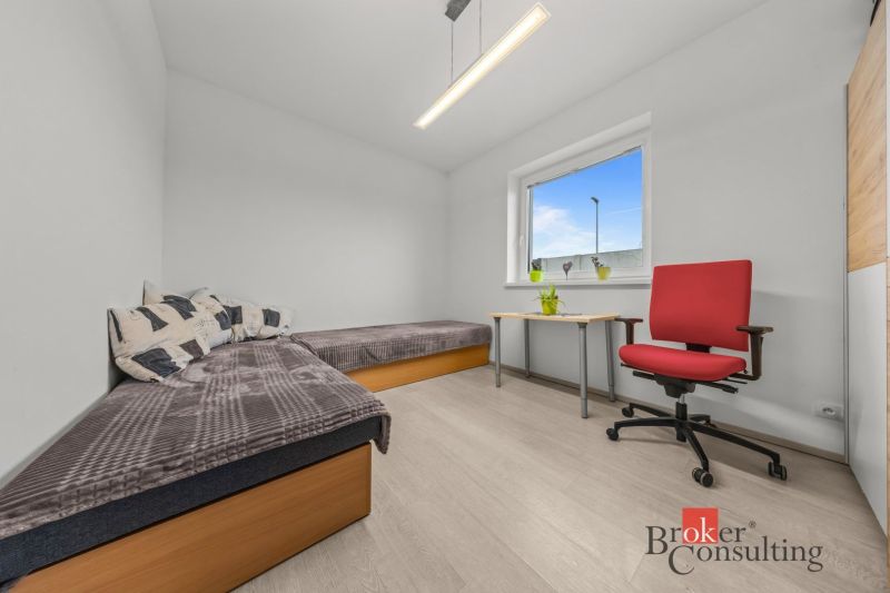 Bedroom in a family house with two beds, a table, and a red armchair.