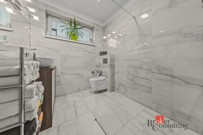 A bathroom in a family house with marble tiles and a wall-mounted toilet.