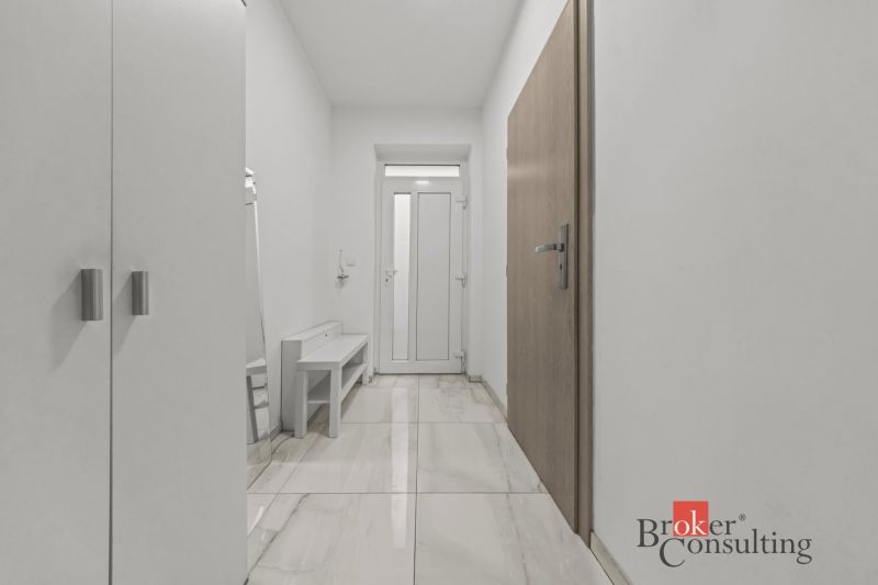 A hallway in a family house with white walls and a shiny floor.