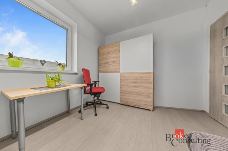 A minimalist room with a desk, a red chair, and a cabinet with a wooden decor.
