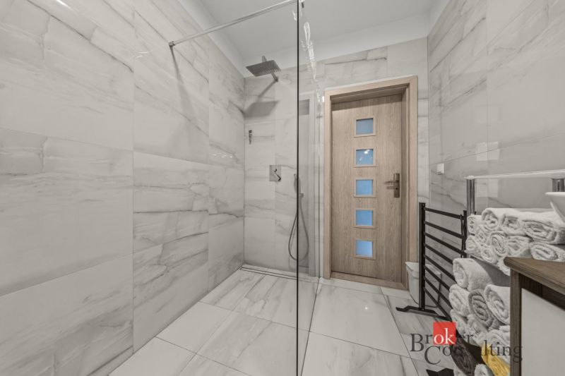 A bathroom in a family house with large-format tiles and a shower corner.