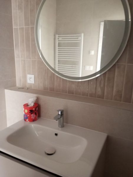 A bathroom with a sink and a round mirror in a 2-room apartment.