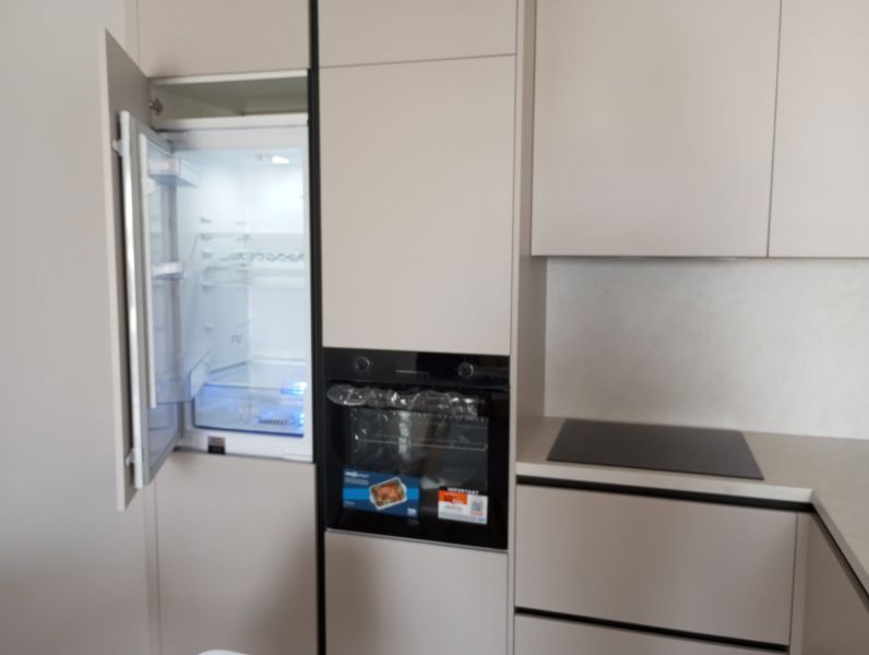 Kitchen unit in a 2-room apartment with an open refrigerator and a cooktop.