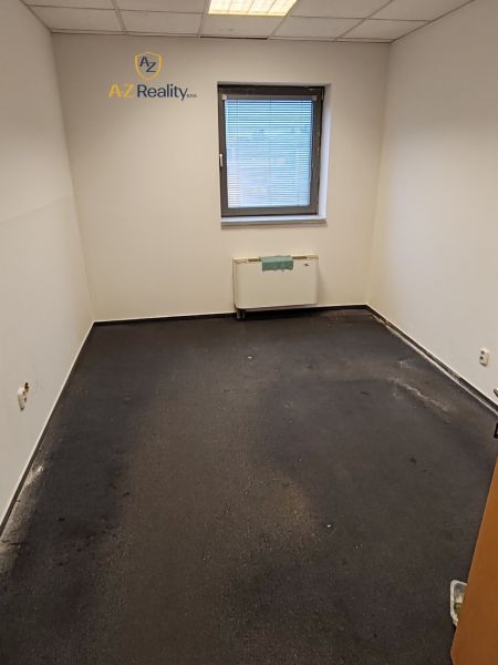Interior of an office with a window, radiator, and dark-colored flooring.