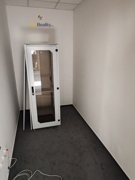 A small office room with a metal cabinet on a dark floor with a wood decor.