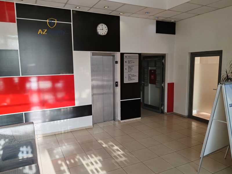 Office interior with an elevator, black and white wall, and a clock on the wall.