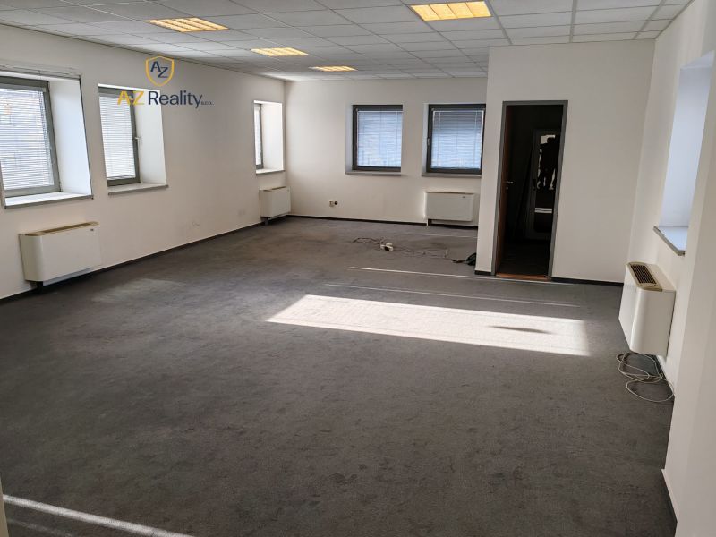 Offices with windows and carpet, bright walls and ceiling lighting.