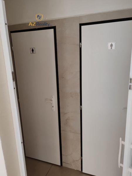 Toilets in commercial premises with white doors and a neutral wall.