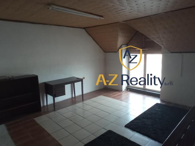 The interior of a building with tiled flooring, a writing desk, and a window, with a carpet on the floor.