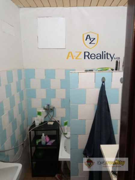 A bathroom in a building with a wooden ceiling and blue tiles.